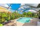 Inviting screened-in pool featuring a sun shelf, brick paver deck, and lush tropical landscaping at 1358 Cielo Ct, North Venice, FL 34275