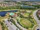 Aerial view of the community clubhouse with a pool, playground, tennis courts, and green spaces surrounded by lakes at 14309 Carolina Sky Pl, Lakewood Ranch, FL 34211