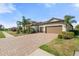 Beautiful single-story home featuring a three-car garage, tile roof, brick driveway, and mature landscaping at 14309 Carolina Sky Pl, Lakewood Ranch, FL 34211