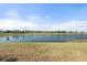 Expansive view of a tranquil pond surrounded by lush grass and distant trees under a clear blue sky at 14309 Carolina Sky Pl, Lakewood Ranch, FL 34211