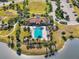 Aerial view of the community pool and clubhouse, surrounded by lush landscaping, playground, and a picturesque lake at 14309 Carolina Sky Pl, Lakewood Ranch, FL 34211