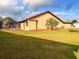 Backyard view of stucco home with clay tile roof and mature landscaping, including a screened-in lanai at 1438 Vermouth Ln, Punta Gorda, FL 33983
