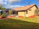 Backyard view of stucco home with clay tile roof featuring mature landscaping, including a screened-in lanai at 1438 Vermouth Ln, Punta Gorda, FL 33983