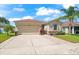 Inviting home with a two-car garage, lush green lawn, brick walkway, and mature landscaping at 1717 Bonita Bluff Ct, Ruskin, FL 33570