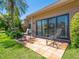 Patio on the rear of the home with a table, chairs, tropical landscaping, and sliders into the property at 1720 Kestral Park S Way # 49, Sarasota, FL 34231