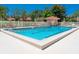 Community pool area with safety fence, umbrellas, lounge chairs, and depth markings at 1720 Kestral Park S Way # 49, Sarasota, FL 34231