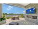 Covered patio with brick accent wall, fireplace, TV and seating area overlooks serene lake at 17946 Cherished Loop, Bradenton, FL 34211