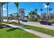 Community entryway featuring lush landscaping, a decorative tower, and a variety of vehicles passing through at 19138 Kirella St, Venice, FL 34293