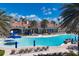 Resort-style pool area with blue umbrellas, lounge chairs, and lush palm trees at the IslandWalk clubhouse at 19138 Kirella St, Venice, FL 34293