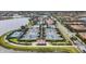 Aerial view of tennis courts with blue shades, a clubhouse, a pool, and surrounding residential homes and water features at 19138 Kirella St, Venice, FL 34293