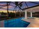 Screened-in pool and spa area with palm trees and views of the water at sunset at 238 Island Cir, Sarasota, FL 34242