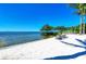 Serene beach view with Adirondack chairs on the white sand by the bay under a clear blue sky at 241 Sapphire Lake Dr # 201, Bradenton, FL 34209