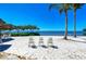 Relaxing beach view with Adirondack chairs on the white sand by the bay under a clear blue sky at 241 Sapphire Lake Dr # 201, Bradenton, FL 34209