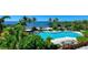 Stunning pool area surrounded by tropical trees and a view of the ocean at 241 Sapphire Lake Dr # 201, Bradenton, FL 34209