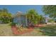 Side view of the home featuring mature trees, tropical plants, and fresh mulch at 301 Angelico Dr, Nokomis, FL 34275