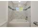 Clean bathtub area showcasing stylish marble-look tile, shower and mosaic accents and a bright window at 3090 6Th St, Sarasota, FL 34237