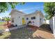 Charming home features a yellow front door, modern lighting fixtures, and professionally landscaped front yard at 3090 6Th St, Sarasota, FL 34237
