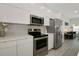 Modern kitchen features stainless steel appliances, light countertops, and white cabinetry with view to the living room at 3090 6Th St, Sarasota, FL 34237