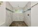 Walk-in shower with pebble floor and white tile with blue accent stripe at 3090 6Th St, Sarasota, FL 34237