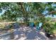 Serene backyard with brick patio featuring blue Adirondack chairs under the shade of a large tree with lush landscaping at 3336 Pembrook Dr, Sarasota, FL 34239