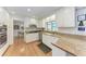 Well-lit kitchen featuring white cabinets, granite countertops, and stainless steel appliances, alongside modern fixtures at 3336 Pembrook Dr, Sarasota, FL 34239