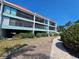 Three-story condos with balconies, red tile roofing, and well-maintained landscaping along a paved walkway at 3805 E Bay Dr # 302, Holmes Beach, FL 34217