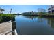 Scenic canal view from a wooden dock, featuring calm waters reflecting the buildings and lush greenery at 3805 E Bay Dr # 302, Holmes Beach, FL 34217