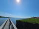 Picturesque view of a wooden dock leading out to tranquil waters, framed by green hedges under a clear sky at 3805 E Bay Dr # 302, Holmes Beach, FL 34217