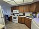 Kitchen with white appliances, wood cabinets, and laminate floors at 3805 E Bay Dr # 302, Holmes Beach, FL 34217