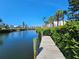 Peaceful water view from a dock, bordered by hedges and palm trees, with building in the distance at 3805 E Bay Dr # 302, Holmes Beach, FL 34217