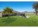 Expansive backyard featuring a well-maintained lawn, palm trees, and a screened patio with an outdoor seating area at 3889 Canopy Way, Sarasota, FL 34235