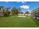 Lush backyard with manicured lawn, tropical plants, and a cozy fire pit seating area near the screened-in patio at 3889 Canopy Way, Sarasota, FL 34235