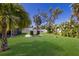 Serene backyard featuring lush green grass, tropical landscaping, a screened patio, and a cozy fire pit area at 3889 Canopy Way, Sarasota, FL 34235