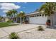 Well-maintained home with a long driveway and well manicured lawn lined with palm trees and rock features at 3889 Canopy Way, Sarasota, FL 34235
