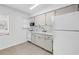 Galley kitchen featuring white appliances and cabinets with a tile backsplash at 4444 Swift Rd # 25, Sarasota, FL 34231