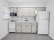 Galley kitchen featuring white appliances and cabinets with a tile backsplash at 4444 Swift Rd # 25, Sarasota, FL 34231