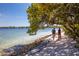 Two people walk on the beach with a stroller near lush foliage, offering a picturesque oceanside view at 4802 51St W St # 107, Bradenton, FL 34210