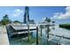 Dock with boat and lift overlooking the water and lush landscaping on a bright day at 4968 Gulf Of Mexico Dr # Villa 22, Longboat Key, FL 34228