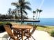 Outdoor patio featuring a wooden table set, green grass, and stunning waterfront views with swaying palm trees at 4968 Gulf Of Mexico Dr # Villa 22, Longboat Key, FL 34228