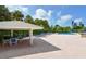 Pool area with shaded seating and lounge chairs under palm trees at 4968 Gulf Of Mexico Dr # Villa 22, Longboat Key, FL 34228