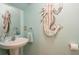 Coastal bathroom features a pedestal sink, mirror, and mermaid wall art at 5346 Neil Dr, St Petersburg, FL 33714