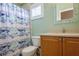 Bathroom featuring seafoam green walls, tile floors, blue shower curtain, and oak vanity with beige countertop at 5346 Neil Dr, St Petersburg, FL 33714