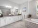Modern bathroom with double vanity, white cabinets, granite counters, and separate tub at 603 165Th E St, Bradenton, FL 34212