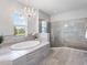 Elegant bathroom featuring a soaking tub, chandelier, and glass-enclosed shower at 603 165Th E St, Bradenton, FL 34212