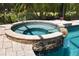 Close up of a unique hot tub, with stone accents, integrated into a luxurious pool setting at 6231 Cypress Bend Ct, University Park, FL 34201