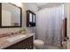 Cozy bathroom featuring a vanity with granite countertop and tiled shower with curtain at 6523 Blue Grosbeak Cir, Lakewood Ranch, FL 34202