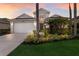 Charming home with lush landscaping, a two-car garage, and a beautiful lawn with palm trees at sunset at 6523 Blue Grosbeak Cir, Lakewood Ranch, FL 34202