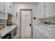 Bright laundry room with white appliances, storage cabinets, and a white door to the garage at 801 E 5Th St, Englewood, FL 34223