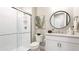 Bright bathroom featuring a tiled shower with glass door and modern vanity with round mirror at 801 Seascape Pl, Sarasota, FL 34240