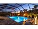Enchanting screened-in pool area with a lounge, lighting, water feature, spa, and lush landscaping at dusk at 801 Seascape Pl, Sarasota, FL 34240